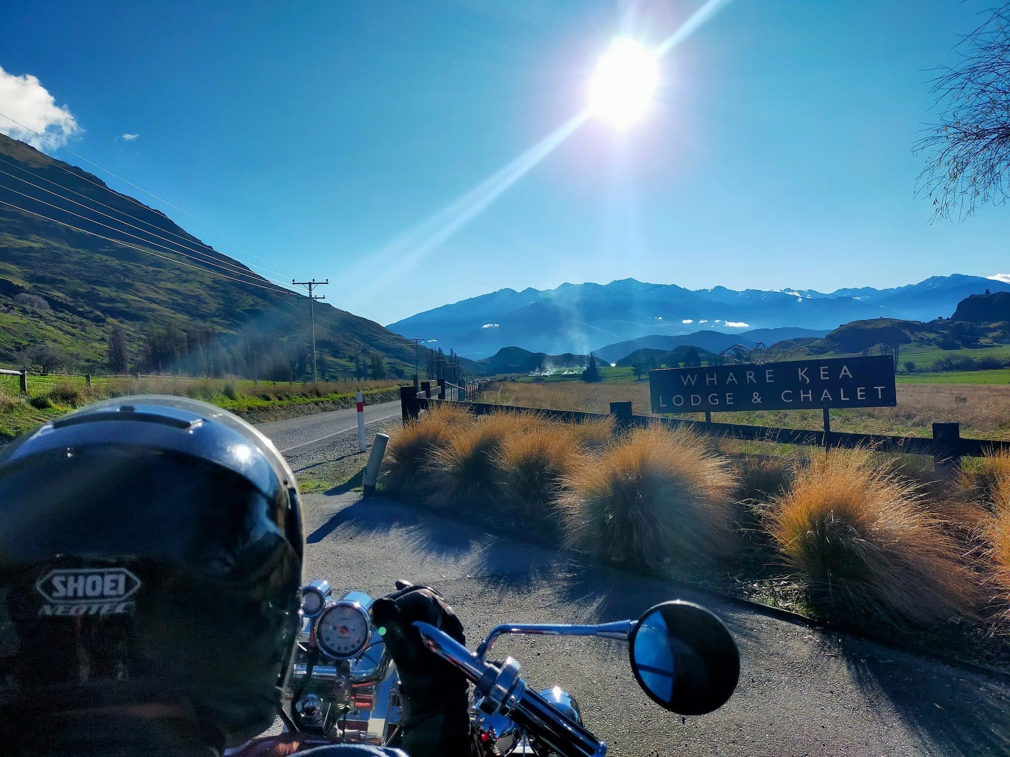 Rider's helmet and mirror on a sunny road through tussock country