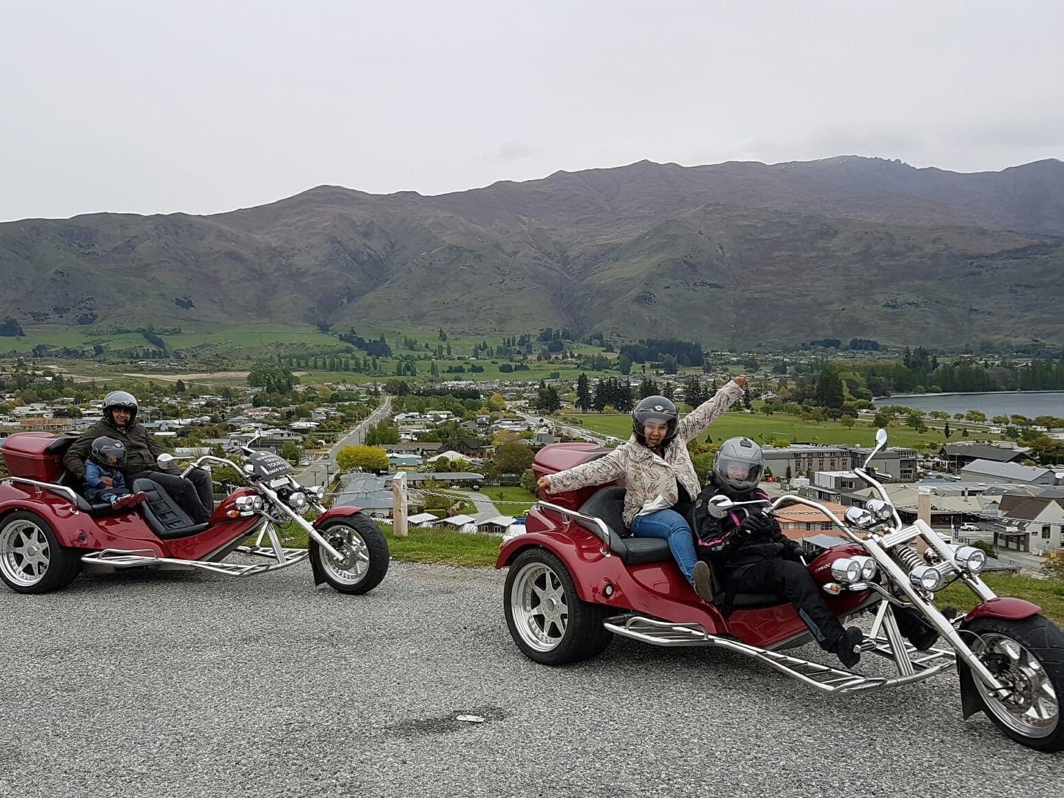 Two trikes with waving guests and a mountain backdrop